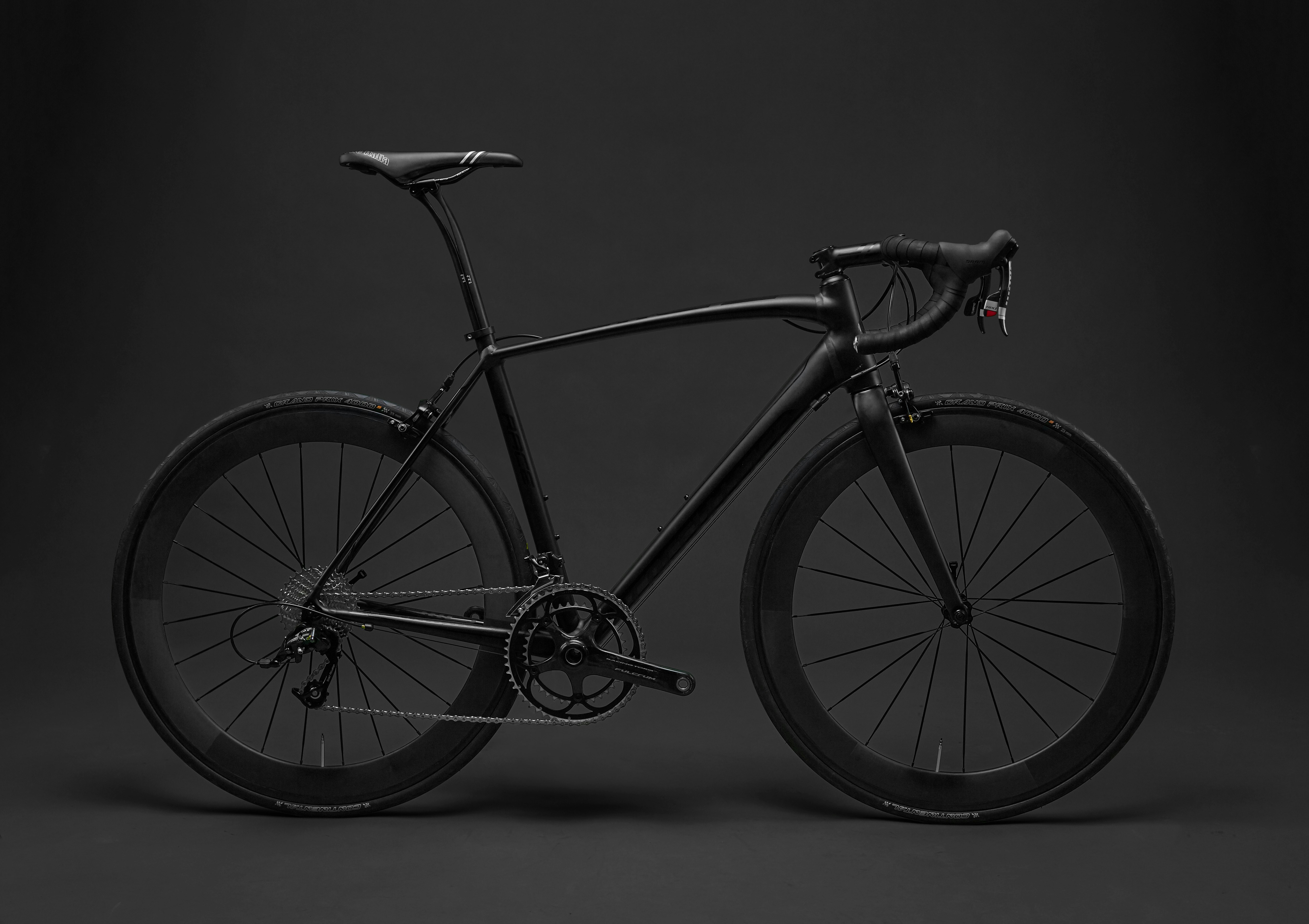 Custom road bike frame leaning against a workshop wall